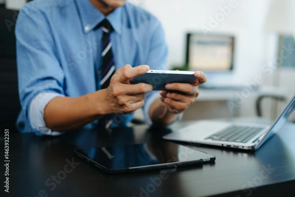 Fototapeta Businessman using smartphone and working on laptop computer  Woman freelancer online working in office