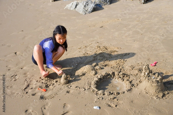 Fototapeta A girl is playing in the sand on the beach.