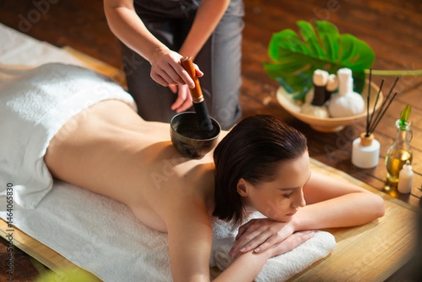 Obraz Young woman getting massaging treatment over exotic background. Spa, healthcare and recreation concept.