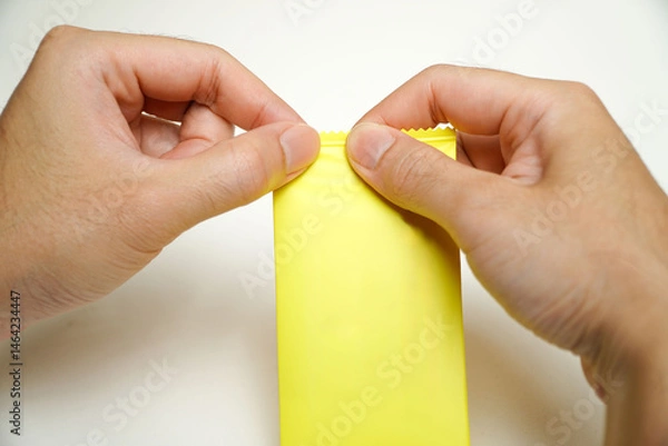 Obraz man's hand holding yellow condom isolated on white background