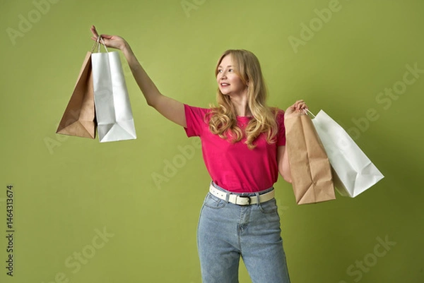 Fototapeta Happy woman enjoying shopping with multiple bags against green background  