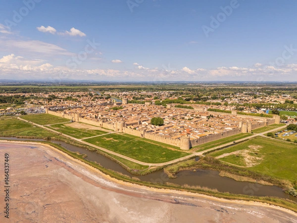 Fototapeta Aigues-Mortes, Camargue, France, medieval city with its surrounding walls, the Constance Tower, typical southern french houses and the salt marshes