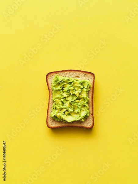 Fototapeta smashed avocado on toasted slice of sandwich bread, empty background, top view, yellow background
