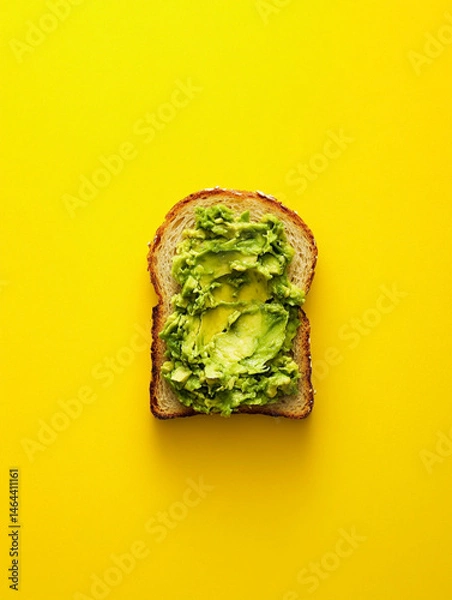 Fototapeta smashed avocado on toasted slice of sandwich bread, empty background, top view, yellow background
