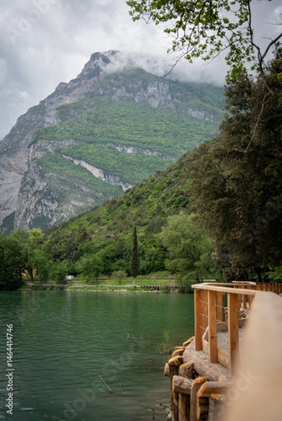 Fototapeta Stunning View Of Lake Toblino In Italy, Framed By Trees With A Majestic Mountain In The Background