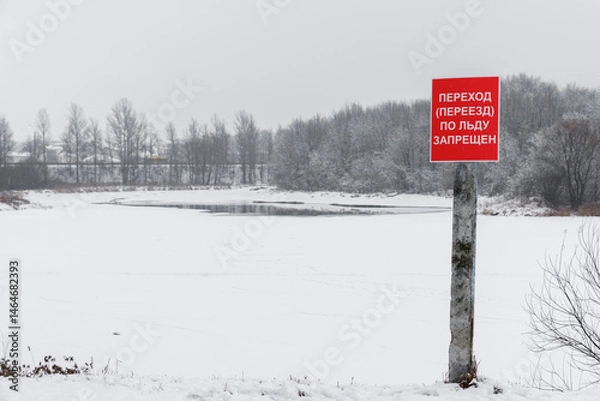 Fototapeta A sign prohibiting ice access is mounted on a concrete pole in front of the reservoir.