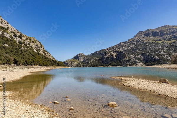 Fototapeta A high altitude dry lake on the Spanish island of Mallorca with green mountains and blue sky