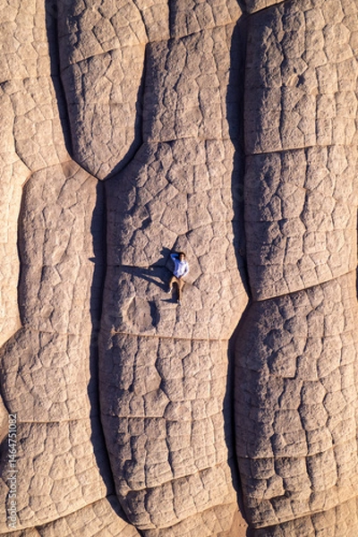 Fototapeta Top down aerial of a man laying on white sandstone rocks at White Pocket in Vermillion Cliffs of Northern Arizona.  Photographed with a drone at sunset.
