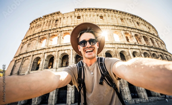 Fototapeta Smiling tourist visiting Coloseum in Rome, Italy - Handsome young man taking selfie with smart mobile phone device - Traveler with backpack enjoying summer vacation - Travel and technology concept
