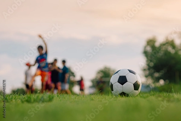 Fototapeta Action sport outdoors of kids having fun playing soccer football for exercise in community rural area under the twilight sunset sky. Picture with copy space.