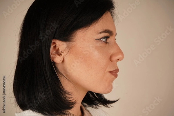 Obraz The ear of a woman is captured up close, with loose, dark hair softly cascading around it. The image highlights subtle beauty and natural elegance. A serene and detailed portrayal.