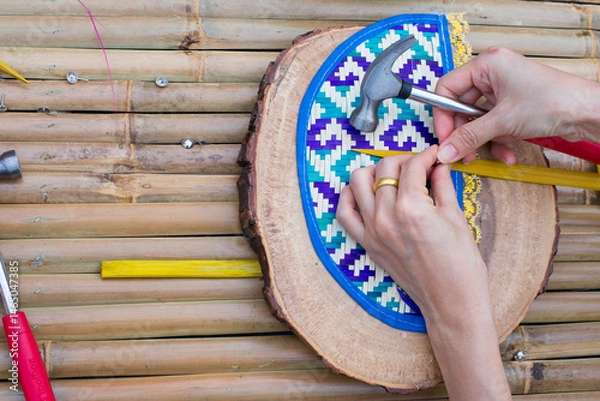 Fototapeta Hand of craftsman using hammer and chisel on wood background.