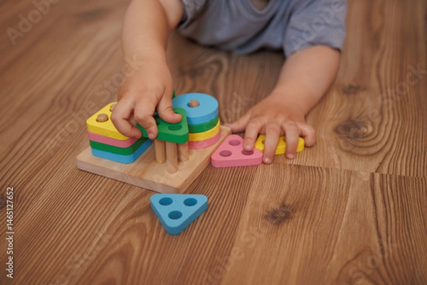 Obraz Close-up of child's hands playing with wooden educational toy-sorter. Horizontal photo. Concept of learning through play, fine motor skills and early childhood development