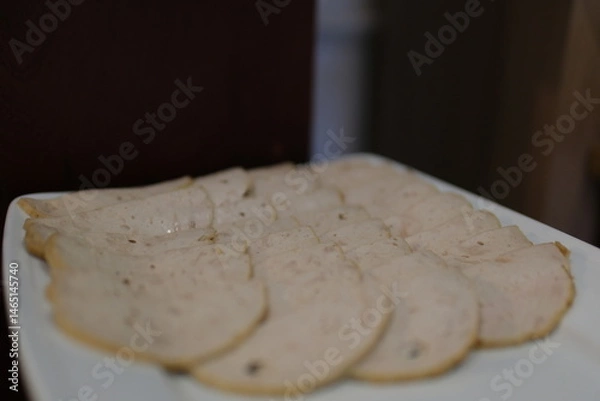 Obraz A view of a hand holding pieces of processed deli turkey slices over toast. High quality photo