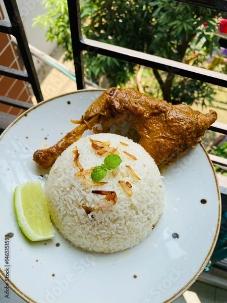 Fototapeta Chicken stew and rice dish served on a white plate on a wooden table. Delicia African chicken stew with rice. Soy Fried Chicken with Rice. 