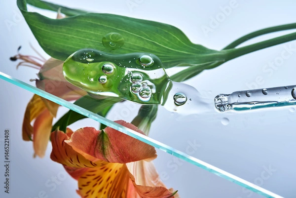 Fototapeta A pipette with a beautiful drop of serum on a background of lily flowers.