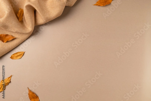 Obraz Brown fabric with leaves on beige as concept background. Copy space