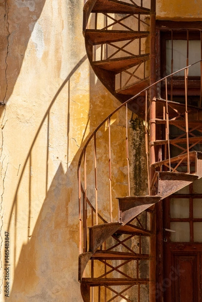 Fototapeta close up at steel rusted spiral staircase with shadows in Gythio, Greece