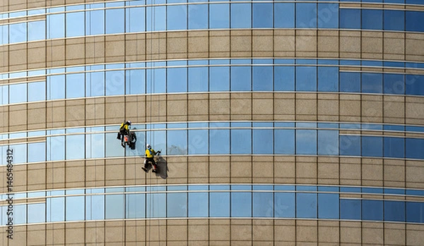 Fototapeta high rise building Window washers cleaning the glass facade of a modern building, skyscraper high risk work.