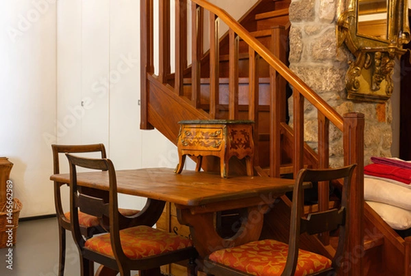 Obraz Table and chairs at the base of a wooden staircase in a classical style furnished apartment interior