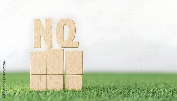 Obraz Wooden blocks spelling "NQ" stand on a grassy surface against a blurred white background
