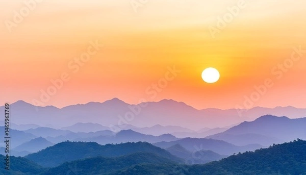 Fototapeta Serene sunset over layered, hazy mountains; warm hues paint the sky