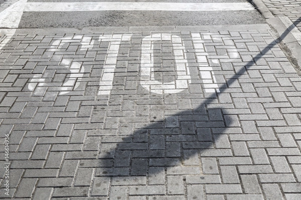 Fototapeta The shadow of a sign Stop against the background of a paved street