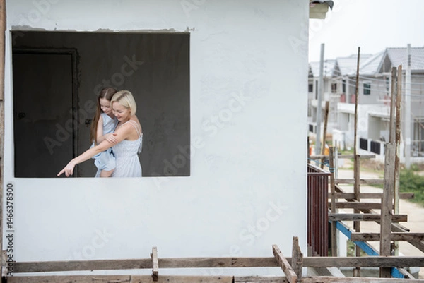Fototapeta Caucasian mother and daughter with Housing Development Under Construction background	