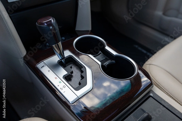 Obraz Portland, OR, USA - Gear shift console of a 2013 Japanese sedan with leather-trimmed handle, wood finish, gear indicators, and dual cup holders in the center section