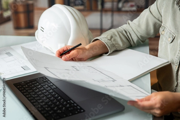 Obraz Architect holding and  working on a technichal blueprint project of new apartments in a multi-storey building .
