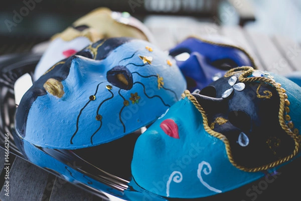 Fototapeta Closeup of beautiful masks made in the venetian style with acrylic paint and decoration, on the silver tray and wooden table