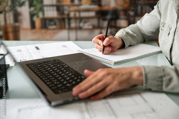 Fototapeta Close up of female hands using laptop and taking notes during the learning or work process