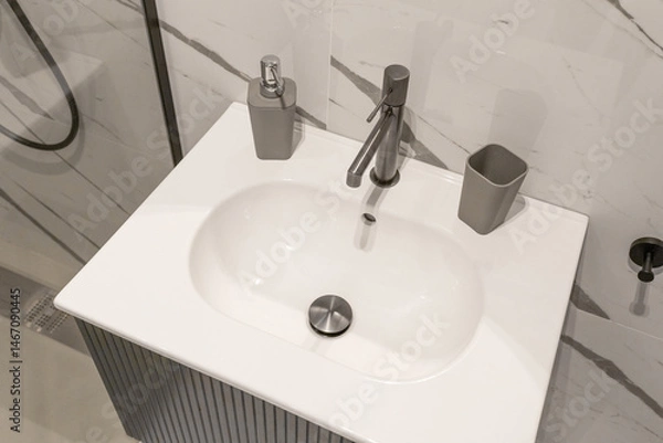 Fototapeta Modern bathroom sink with a minimalist rectangular basin and sleek chrome faucet, complemented by a stylish soap dispenser. 