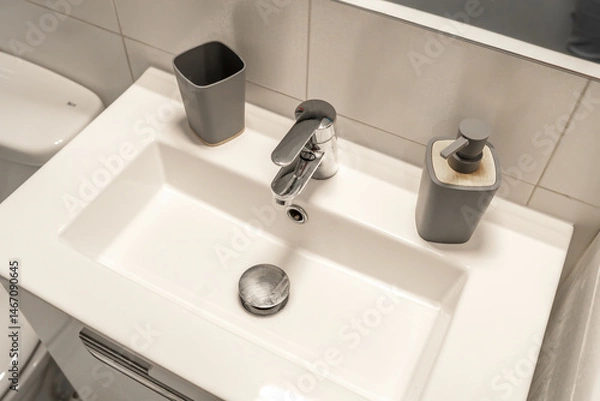Fototapeta Modern bathroom sink with a minimalist rectangular basin and sleek chrome faucet, complemented by a stylish soap dispenser. 