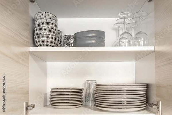 Fototapeta Kitchen cupboard with different clean dinnerware. Shelving with dishes, glasses and cups.