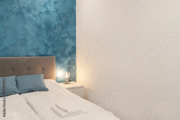 Fototapeta Close up of  bed in minimal, modern and luxury bedroom, Grunge Blue wall. Bedside tables Modern lamps.