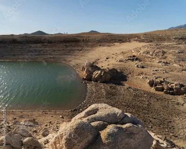 Fototapeta Panoramic view of a low-water reservoir surrounded by rocky slopes and mountains in Darnius, Catalonia, Spain, during a drought.