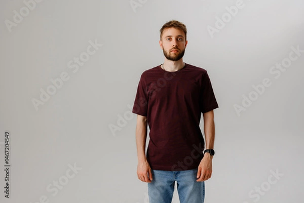 Fototapeta Young man standing confidently in casual clothing against a neutral background during a studio photoshoot