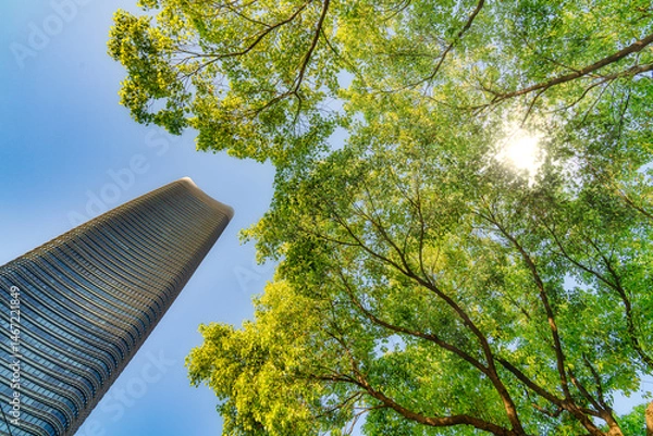 Fototapeta Sustainable glass office building with trees reflects corporate environmental responsibility. Modern eco office reduces carbon dioxide. Green environment concept