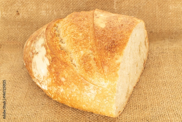 Fototapeta One half of a loaf of bread with a jute bag, close-up.