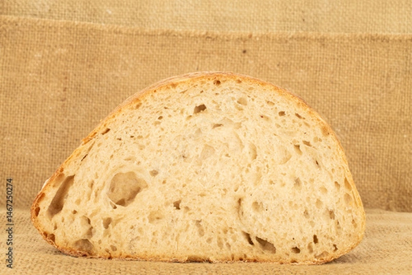 Fototapeta One piece of hearth bread on jute cloth, close-up.