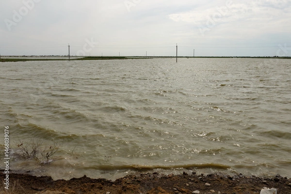 Fototapeta Flooded steppe landscape with power line poles submerged in water after flood in Kazakhstan