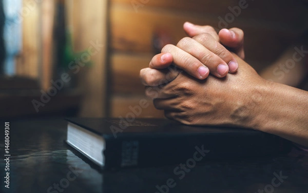 Obraz Close up of a man praying, hands clasped together on Bible, devotional concept.