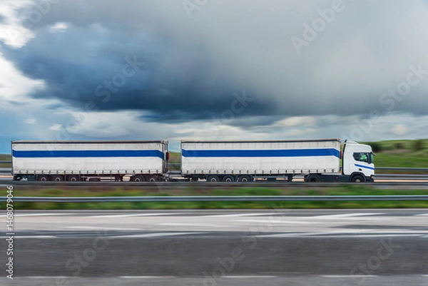 Fototapeta Duo-trailer driving on a highway, panning shot with motion blur, side view.