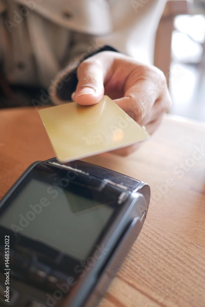 Fototapeta Customer making a payment with card at a cafe in the morning