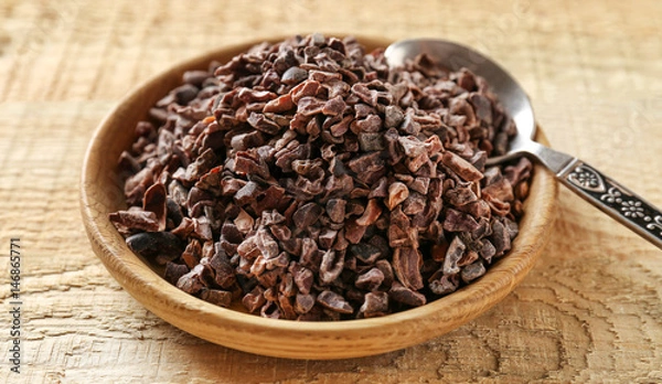 Fototapeta Bowl with aromatic cocoa nibs on wooden table