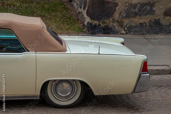 Fototapeta Retro car on a background of cobblestones. The back of the car. Side view.