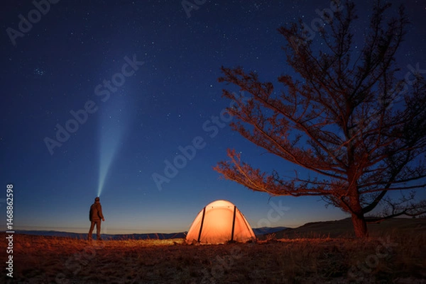 Obraz Silhouette of alone hiker man at his illuminated camp tent at starry night