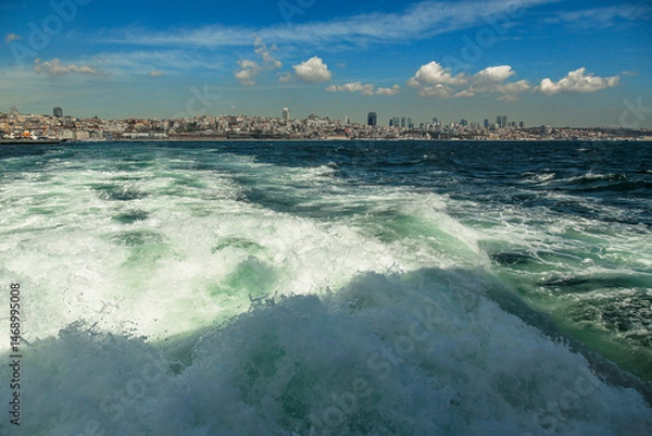 Fototapeta Spring, Istanbul view from the sea. Panorama of the city with a beautiful wave and clouds in the background . high-rise buildings, Turkey
