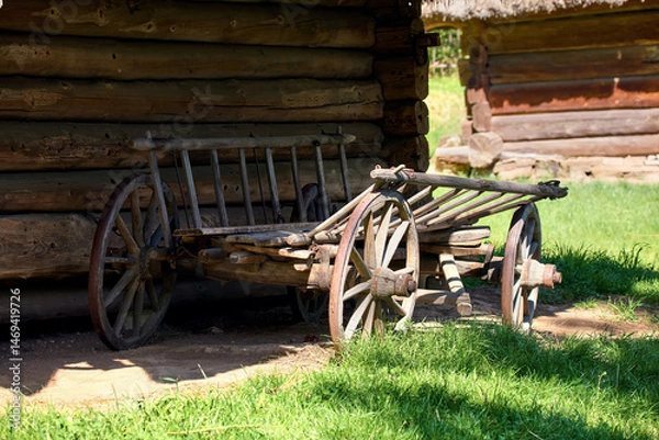 Fototapeta  old wooden cart with large wheels standing near a wooden Ukrainian house in the yard